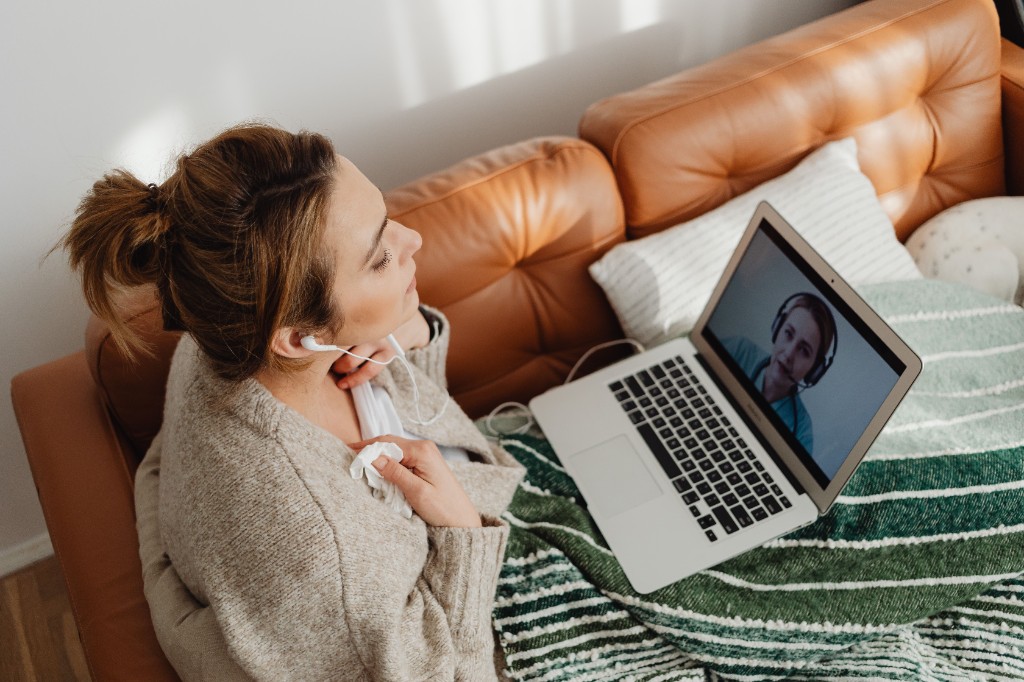 Eine Frau spricht auf dem Sofa per Videoanruf mit einer Beraterin