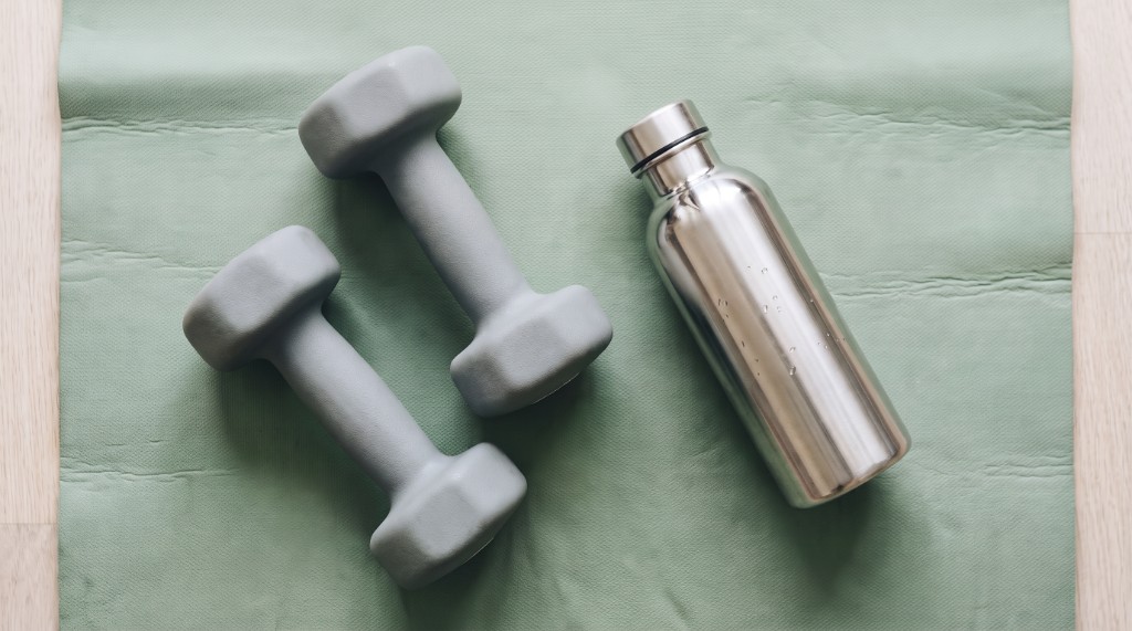 Hanteln und Trinkflasche auf einer Trainingsmatte